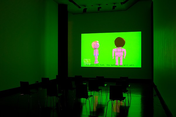 Installation view of a dark room with three walls, ceiling and floor visible. On the center wall we can see a large video projection. In the video still, we can see two animated figures in full body against a green screen. The figures are doll-like, similar to those in Playmobil or LEGO. The figure to the left is male. He is seen in profile, turned to the right. He has light skin, short blonde quiff, and is wearing baby blue briefs with a white lining. To the left of him, slightly closer to us, we can see what appears as a female figure. She is facing away from us, and we can see green bra straps on her back. She has light skin, and short brown hair. In the left bottom corner of the projection, we can see a logo that looks like the outline of two capital letters "N" in white cartoonish font. Underneath it, we can read the text "xtranormal" in white modern font. At the bottom of the projection, we can see the captions "The more you fuck, the better you will edit" in grey typewriter font. In front of the projection, four black chairs with square backrests and chrome legs stand in rows of three. To the left, obscuring the corner where the center wall and the left wall meet, we can see a narrow black curtain stretching from just below the ceiling to floor. The floor is dark and polished, and reflects the green light from the projection. In the ceiling, we can see spot lights that are turned off.