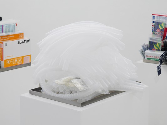 Close-up view of shallow metal tray containing a pile of what look like clear, plastic ventilator tubes on a white pedestal.