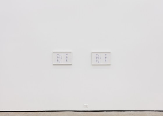 A large white wall with two framed artworks.