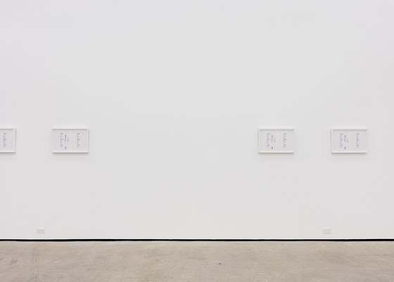 A large white wall with four framed artworks unevenly spaced. One of the frames extends outside the picture.