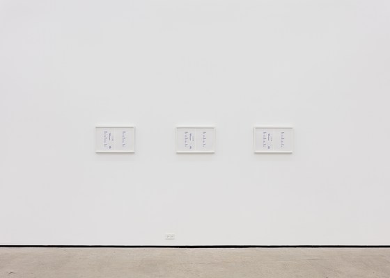 A large white wall with three framed artworks.