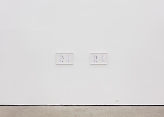 A large white wall with two framed artworks.