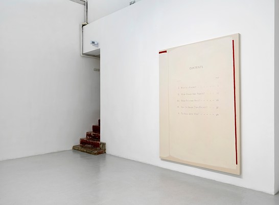 Installation view of a room with two white walls and light grey floor. The two walls meet in a corner slightly to the left of the center of the image, where a narrow doorway is located. In the doorway, we can see a staircase leading up. The lowest step sticks out into the room. The staircase appears to be made from casted concrete, painted in a deep, burgundy red, which has chipped. At the top of the doorway, we can see a white pipe coming out, which continues vertically up towards the ceiling. Above the doorway we can see some form of device, possibly measuring humidity. On the right wall hangs a large, almost square painting. It has almost the same hight as the doorway. On the raw cotton canvas, taking up most of the surface of the painting, the right page of a book has been painted in light beige. To the left of it, we can see a part of the left page. On the right page, we can read a table of contents. At the vertical edge of the right page, we can see the red vertical stripe, which looks like the book cover peeking out. Above the left page, we can see a horizontal stripe painted in the same red.