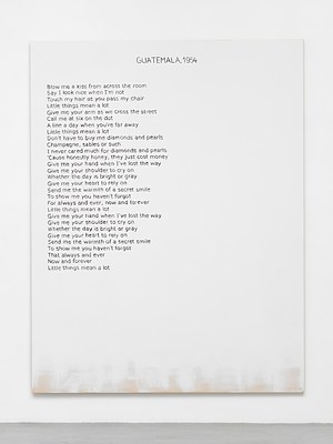 Close view of one of the paintings in the previous installation views. The painting is white except for around the bottom edge, where we can see the raw cotton canvas faded in. Against the white background, we can see a block of black text aligned to the left margin, and a title in capital letters at the top in the center. The text appears hand written, neatly, in sans serif. The title reads "Guatemala, 1954" in all caps and the block of text reads:. "Blow me a kiss from across the room. Say I look nice when I'm not. Touch my hair as you pass my chair. Little things mean a lot. Give me your arm as we cross the street. Call me at six on the dot. A line a day when you're away. Little things mean a lot. Don't have to buy me diamonds and pearls. Champagne, sables or such. I never cared much for diamonds and pearls. 'Cause honey, they just cost money. Give me your hand when I've lost the way. Give me your shoulder to cry on. Whenever the the day is bright or gray. Give me your heart to rely on. Send me the warmth of a secret smile. To show me you haven't forgot. For always and ever, now and forever. Little things mean a lot. Give me your hand when I've lost the way. Give me your shoulder to cry on. Whenever the the day is bright or gray. Give me your heart to rely on. Send me the warmth of a secret smile. To show me you haven't forgot. That always and ever. Now and forever. Little things mean a lot"