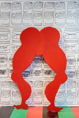 Another detail of the bright red cutout of legs and butt seen in previous installation images. The cutout is a silhouette of the free standing sculpture of the woman in the pink bathing suit. Simplified from the details of bathing suit lines, we can see that the rounded butt forms the shape of a heart, ending in the lips of the vulva. All of the shapes on the silhouette of this body are rounded, the thighs, knee caps, calf muscles and feet arches.