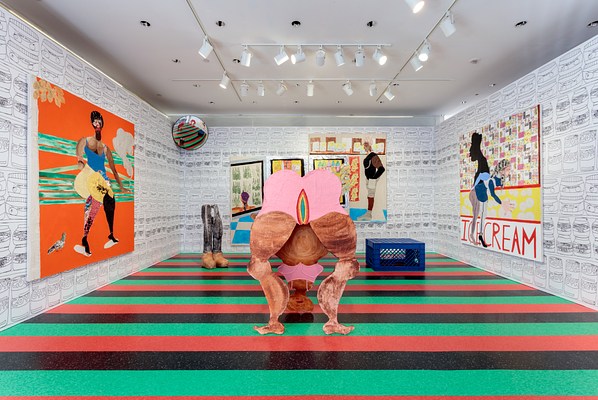 A closer view of the gallery space from inside the glass doors. The ground is covered with green, black, and orange striped laminate flooring. The walls are covered with a black and white wallpaper with a repeated pattern of jars. In what appears to be ink drawing, there are two rows of jars with an "apple sauce" label. The next two rows of jars say "Hellman's Real Mayonnaise". The next two rows say "Goya". These rows repeat in stripes that cover the walls from floor to ceiling. On the wall hang three large paintings. Various sculptures fill the floor, including the woman bending down, and a circular traffic mirror is installed in the back corner to our left.