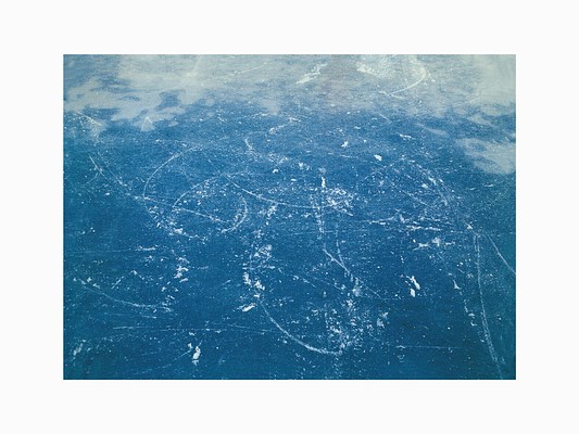Crisscrossing thin white curvy lines drawn by skates on blue ice with wisps of white at the top of the image.