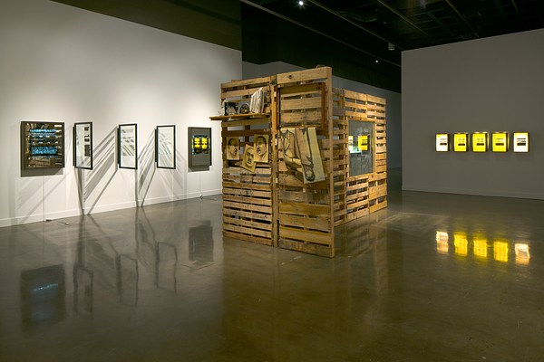 Installation view with a large sculpture in the center of the room made of wood pallets with sketches hung on the sides. Smaller sculptures line the left and right walls.&nbsp;