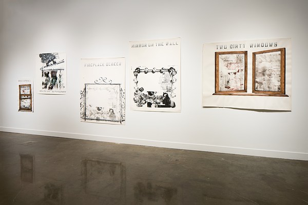 Installation view featuring five prints of varying sizes hung on the gallery wall. The prints are mostly black with large text at the top and some feature images of wooden frames.&nbsp;