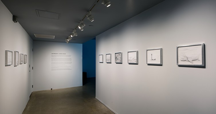 An entry space with framed drawings on left and right walls, wall text straight ahead, and the opening to another space