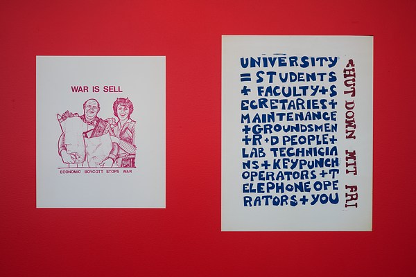 Two graphic protest posters , one supporting economic boycott, the other supporting a walkout, hang side by side on a red wall.