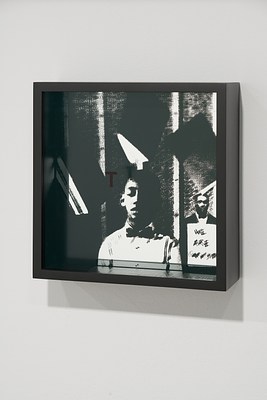 Shadowbox with a letter T on top glass over a silk screened image of a boy in the center, a man behind a sign to the right.