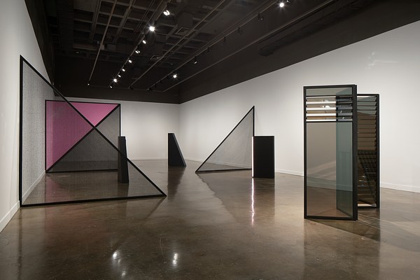 Geometric forms bisect the Gallery, including mirrored rectangles, black and pink  triangles and light towers in the same shapes.