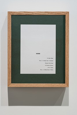 A vertical wooden frame with green matting and a piece of paper on which the  name, Maine and 6 partial addresses are typed.