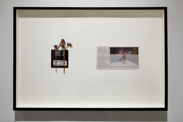  Framed artwork of dried flowers on top of a black floppy disk and a newspaper clipping  with an image of flowers in a vase.