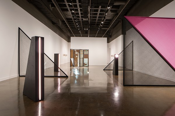 Three black light towers are interspersed with large net triangles. A mirrored louvered  folding screen is in the rear.