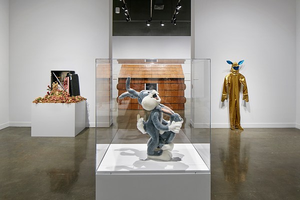 Plush sculpture of bugs bunny in a glass case in the foreground with three other sculptures in the background including a large log cabin.&nbsp;