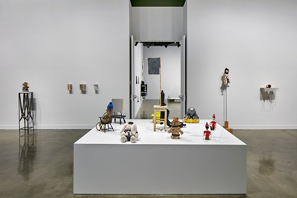An installation view of Nayland Blake's exhibition at the List Center features a white platform in the center with small dolls and stuffed animals on it and small sculptures in the background.&nbsp;