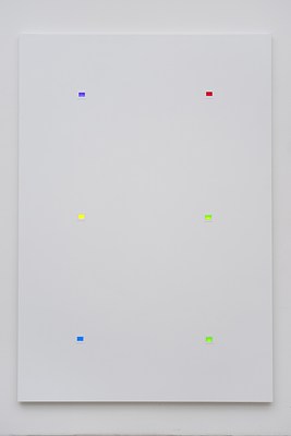 Close view of a painting hanging on a white wall, seen in previous installation images. The painting is in portrait format, and primed in white. About one forth in from the left and right vertical edge of the painting, we can see two columns of three photographic slides symmetrically mounted onto the canvas. The slides are all monochrome, and sit within a white paper frame. In the first row from the left, we can see a purple and a red slide; in the second row, a yellow and green slide; and in the third row, a blue and a green slide. The slides appear lit from behind. Below the painting, we can see a subtle drop shadow on the wall.