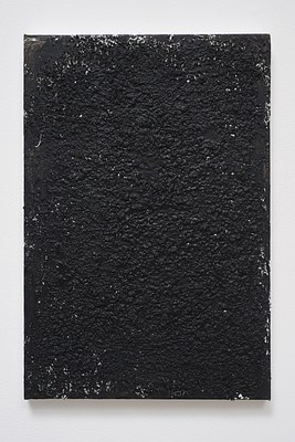 Close view of a painting hanging on a white wall, seen in previous installation images. The painting is in portrait format and almost entirely monochrome. On top of a white painted surface, black paint has been applied. The black paint covers almost all of the surface of the painting aside from some glimpses of the white paint around the edges of the painting. Except from smooth areas around the edges, the surface of the painting is rough, and with visible creases and lumps. Below the painting, we can see a subtle shadow on the wall.