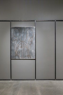 A welded steel drawing sits in between two vertical steel bars on a gallery wall surrounded by other steel bars that form rectangular shapes on the wall.&nbsp;