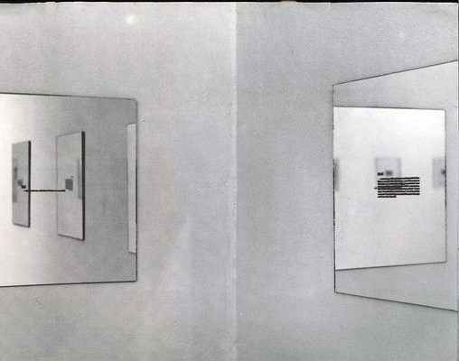 Installation view of a corner in a room and works on the walls. Two walls meet in the center of the image. On the wall to our left, we can see a work in the form of a mirror with small, black text in the center, hanging on the wall. In the mirror, we can see the reflection of the right wall, from out of frame, and three mirrors works with text in the same dimensions and of the same series. On the right wall, we can see another mirror with black text in the center. Reflected in this mirror, we can see a mirror work of the same series hanging on the left wall and out of frame, In that mirror, we can see two additional mirrors reflected from elsewhere in the room. The image is in greyscale.