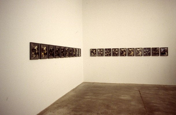 Installation view of the two rows of framed pictures on each of two walls forming the corner of the gallery. From this angle, it's clear that, like the row on our right, the row on our left also has ten framed pictures.