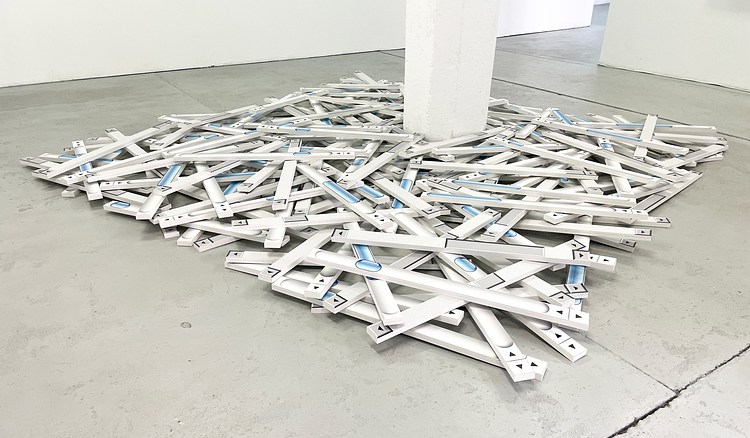 White scrollbar sculptures piled across a gallery's concrete floor