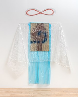 A closer view of the work with garment proportions and horizontally-oriented infinity symbol. An abstract painting with brown and blue marks on a light gold or beige background is veiled by a sheet of semi-transparent, light blue plastic, and over that, a sheet of clear bubble wrap. The blue plastic extends beyond the painting vertically, nearly reaching the floor. The bubble wrap extends beyond the painting horizontally, pinned at the top so that the excess material drapes down like sleeves or towels on hooks. A horizontally-oriented infinity symbol drawn directly on the wall in what looks like red pencil and graphite hovers, centered, above this assemblage.