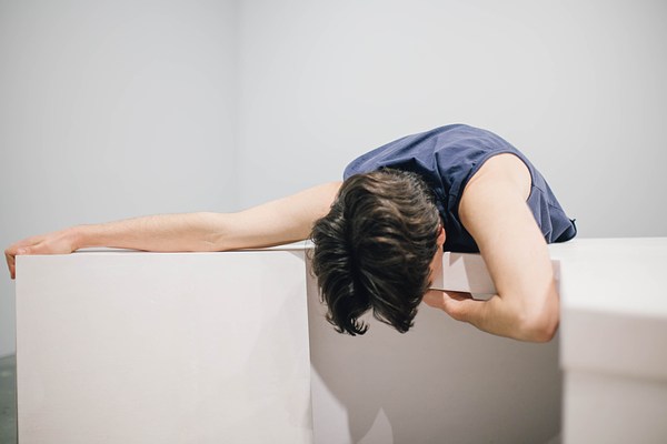 Performance piece where a person draped their body over a sculpture bench with one arm stretched out on the bench and the other bent under the bench.&nbsp;. 